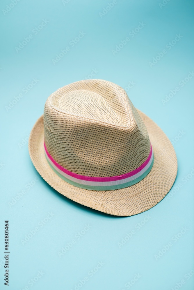 Stylish tan fedora hat with a pink stripe detail against a vibrant blue background