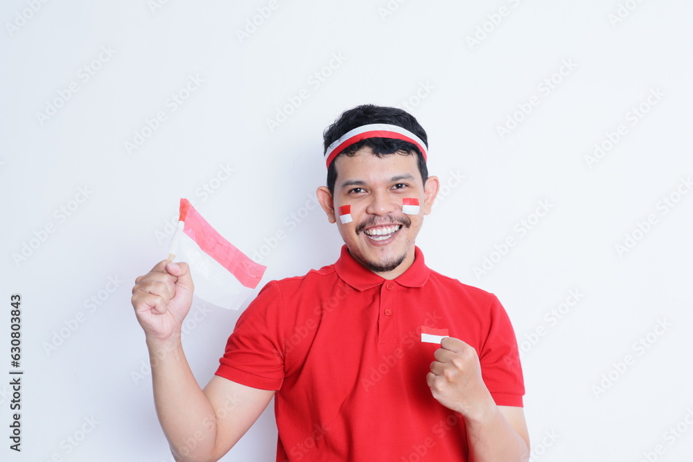 Indonesian man clenched fist, carrying red and white flag, showing excitement when celebrating independence day Indonesian man clenched fist, carrying red and white flag, showing excitement when celebrating independence day