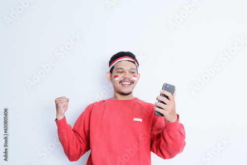 Indonesian man smiling while holding a mobile phone during independence day celebration © IgnatiusHarly