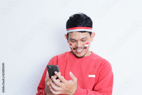 Indonesian man smiling while holding a mobile phone during independence day celebration © IgnatiusHarly