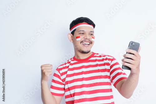 Indonesian man smiling while holding a mobile phone during independence day celebration © IgnatiusHarly
