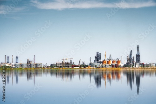 An urban landscape with an industrial area at the center reflecting in the tranquil waters © Yang6/Wirestock Creators