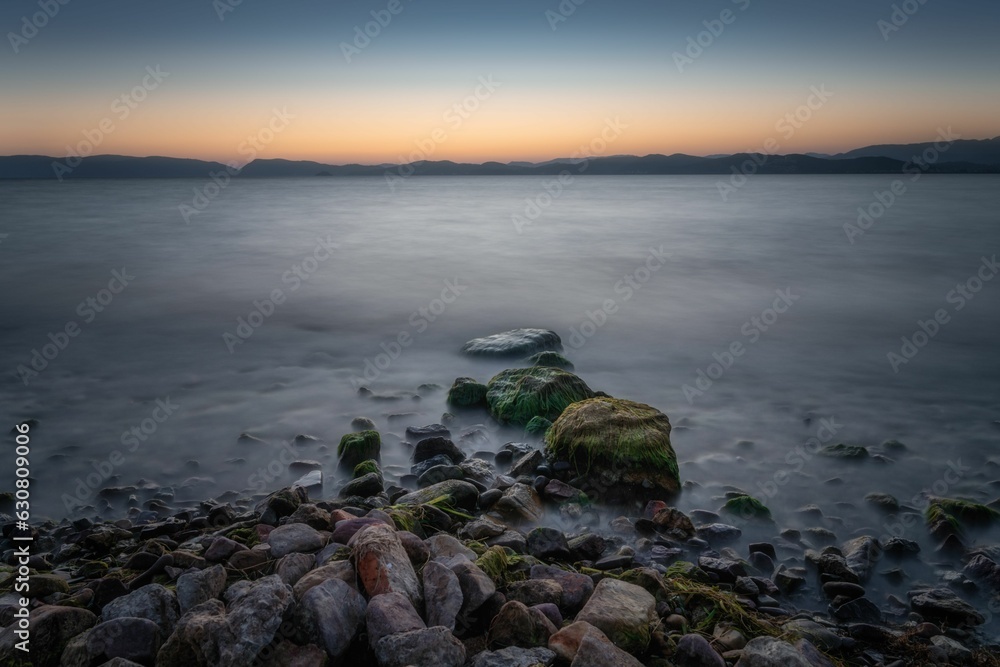 Shoreline beneath a tranquil twilight sky on a foggy day