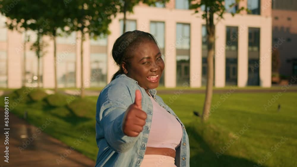 Enthusiastic happy successful African American ethnic student girl satisfied woman outdoors city showing like thumb up consent approval agree like hand gesture agreement support sign recommend smiling Enthusiastic happy successful African American ethnic student girl satisfied woman outdoors city showing like thumb up consent approval agree like hand gesture agreement support sign recommend smiling