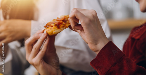 Group of young friends eating pizza at home and having fun