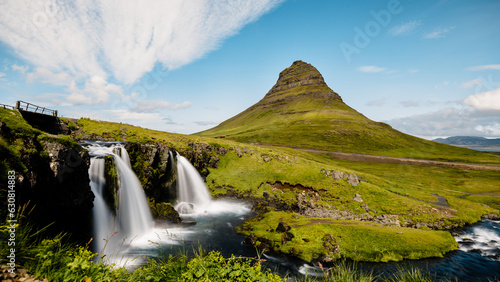 Tranquil Kirkjufell waterfall cascading surrounded by lush mountain terrain in Iceland