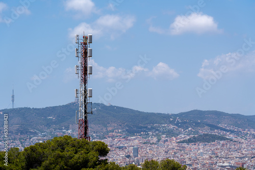 Big tower with antennas and satellites in front of the mountains and the city of Barcelona, no people and clear sky