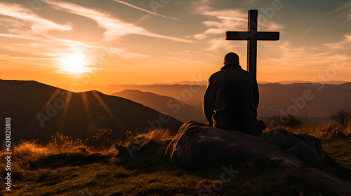 Silhouette of a man kneeling praying at the Cross of Jesus on a hill at sunrise