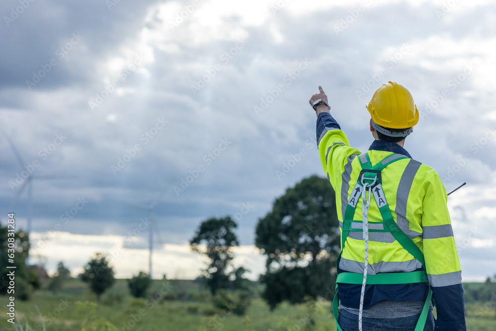 Engineer male working in wind turbines farm back view hand pointing at the sky for future of eco clean energy worker people Engineer male working in wind turbines farm back view hand pointing at the sky for future of eco clean energy worker people