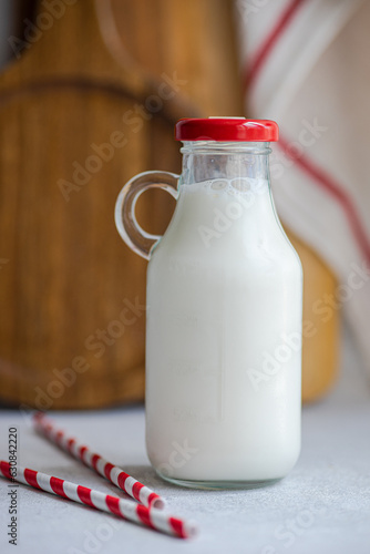 Raw cow milk in vintage bottle near drinking straws against blurred background photo