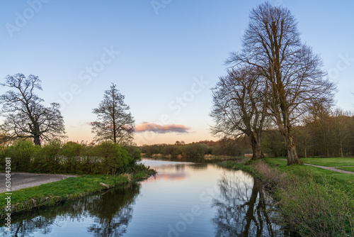 Picturesque landscape with a small river at sunset. Small orange cloud in the sunset sky.