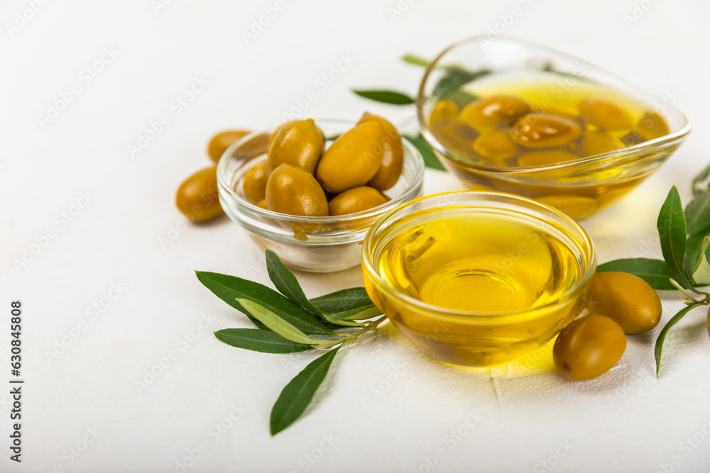Olive oil in a bottle and gravy boat on the kitchen table. Oil bottle with branches and fruits of olives. Place for text. copy space. vegetable oil and salad dressing. Olive oil in a bottle and gravy boat on the kitchen table. Oil bottle with branches and fruits of olives. Place for text. copy space. vegetable oil and salad dressing.
