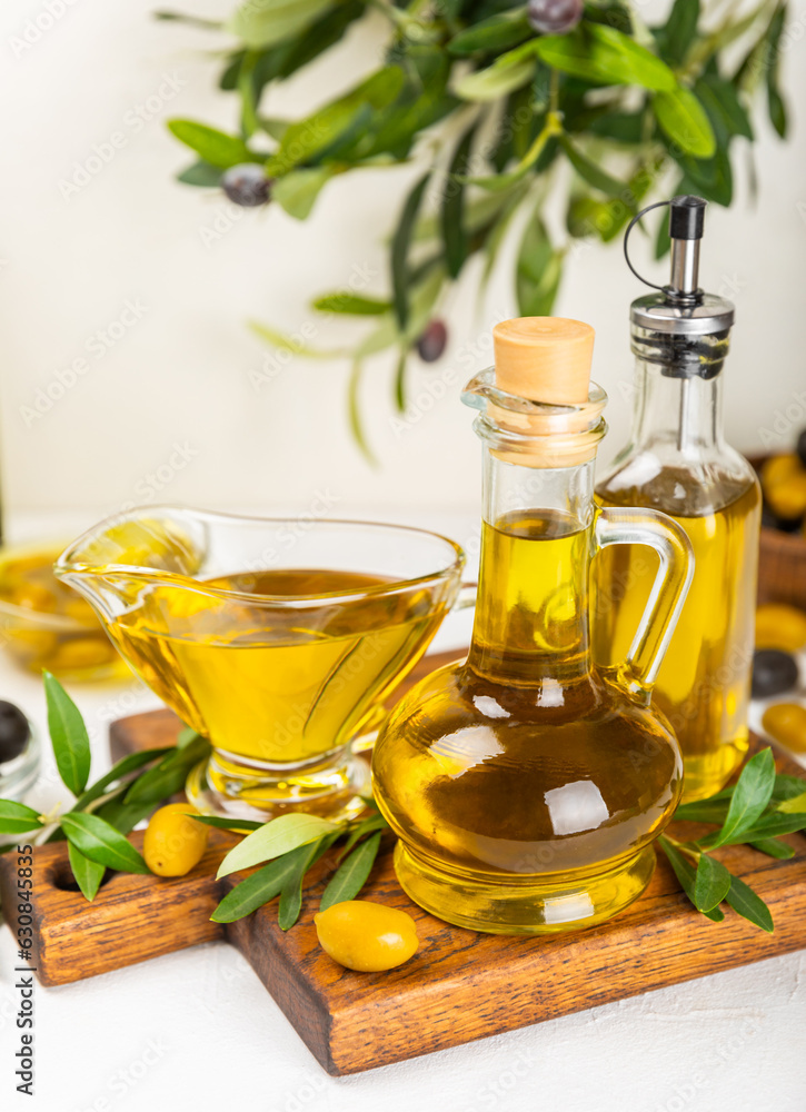 Olive oil in a bottle and gravy boat on the kitchen table. Oil bottle with branches and fruits of olives. Place for text. copy space. vegetable oil and salad dressing. Olive oil in a bottle and gravy boat on the kitchen table. Oil bottle with branches and fruits of olives. Place for text. copy space. vegetable oil and salad dressing.