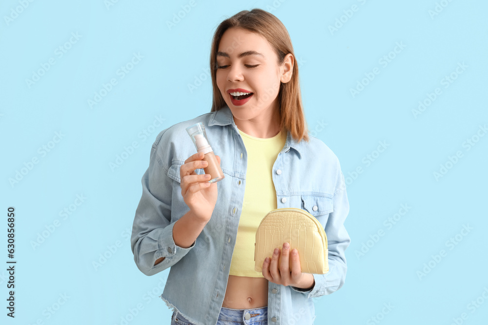 Young woman with makeup foundation and cosmetic bag on blue background Young woman with makeup foundation and cosmetic bag on blue background