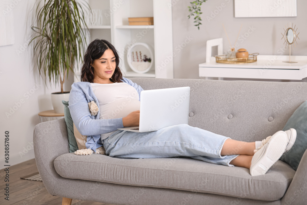 Young pregnant woman working with laptop on sofa at home Young pregnant woman working with laptop on sofa at home