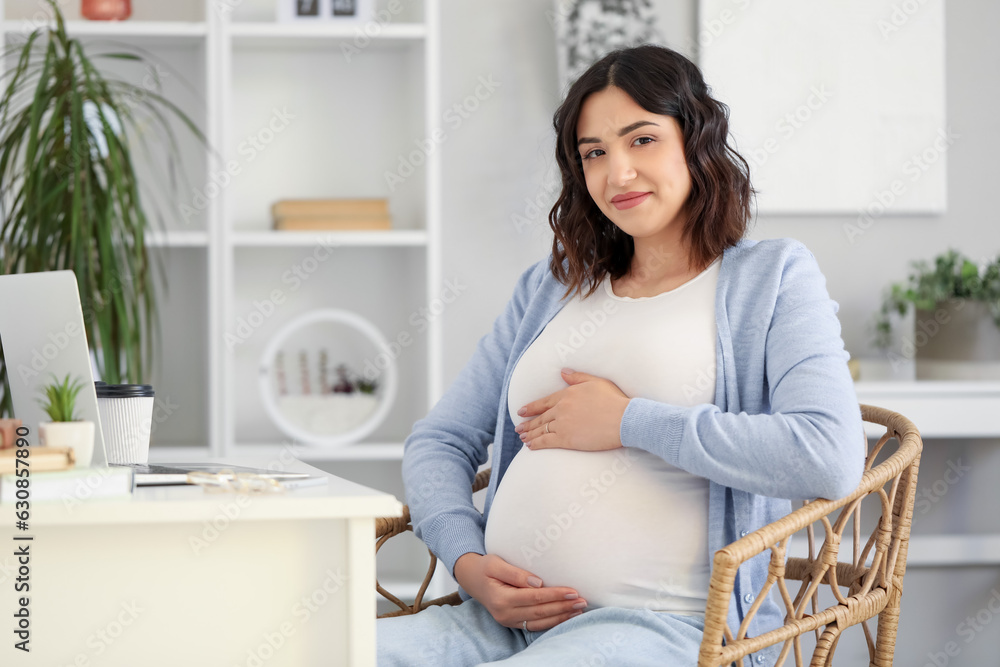 Young pregnant woman working at table in office Young pregnant woman working at table in office