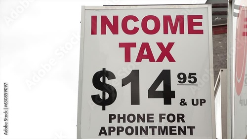 income tax 14 95 15 dollars and up phone for appointment vertical rectangle high hanging sign with income tax writing in red and other caption in black on white background photo