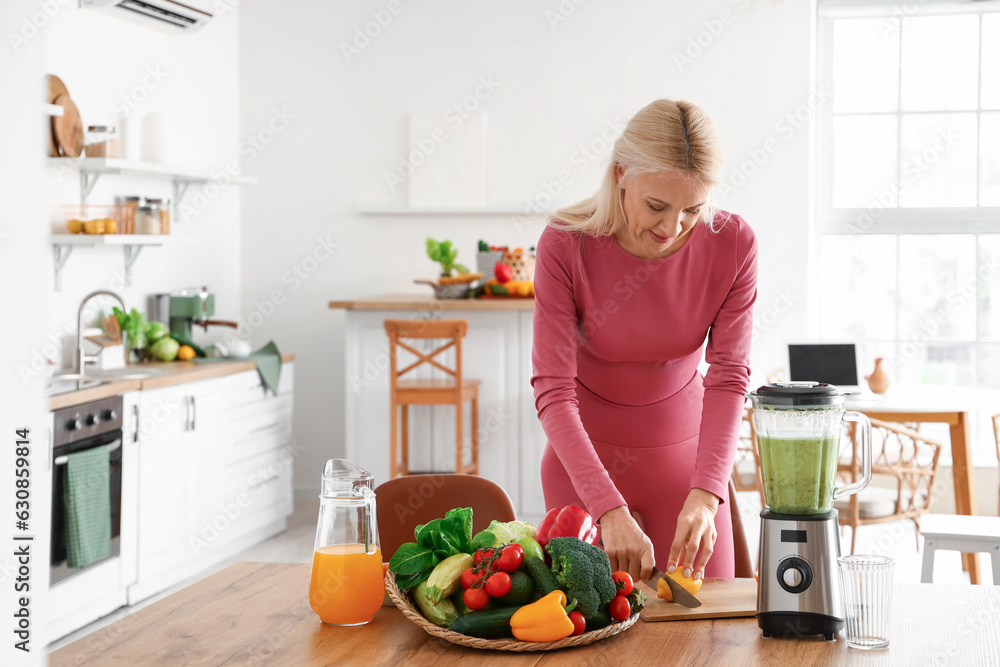 Sporty mature woman cutting lemon for healthy smoothie in kitchen Sporty mature woman cutting lemon for healthy smoothie in kitchen