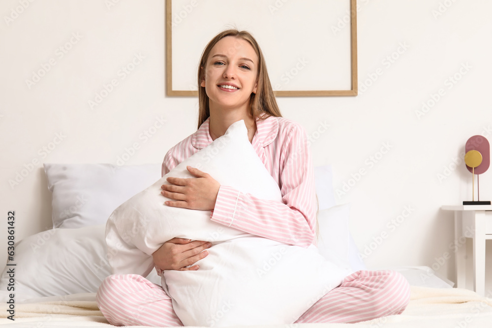 Pretty young woman with soft pillow sitting on bed Pretty young woman with soft pillow sitting on bed