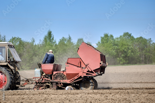 Farmer field with potato planter during spring planting.