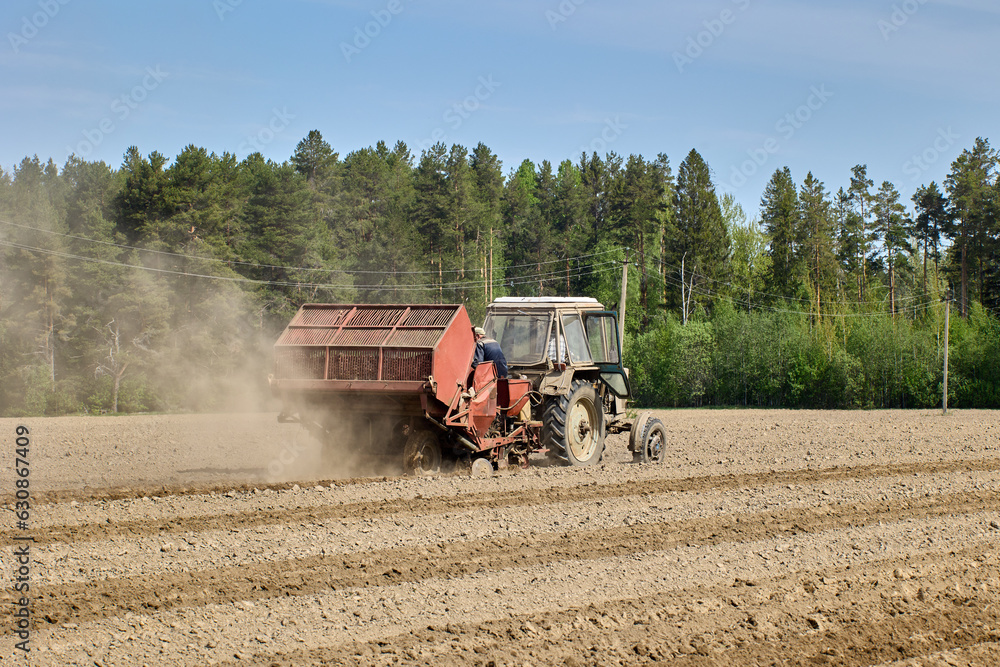 Fototapeta premium Agricultural field with potato planter during spring sowing.