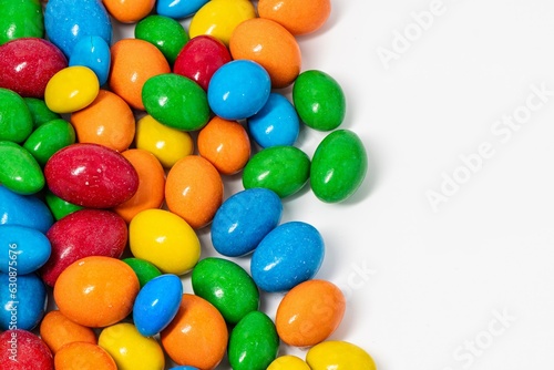 Multi-colored round candies are scattered on a white background. Glazed peanuts in chocolate.