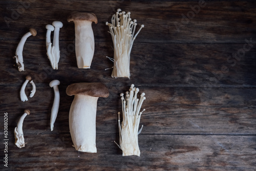 Various edible Asian mushrooms. Enoki, shimeji, shiitake, tea tree, royal oyster mushrooms. Set of vegetables. Dark photo natural light.  photo