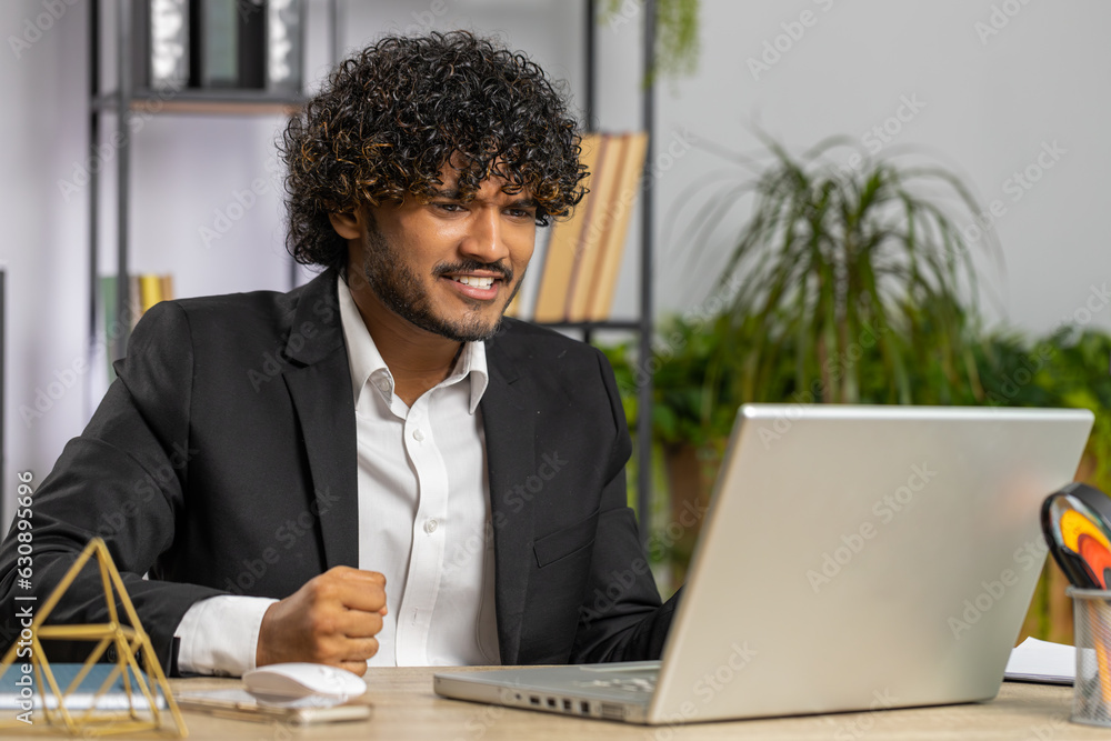 Irritated tired indian business man while working on laptop, unexpected online website problem, computer virus data loss by hacking. Freelancer feeling mad about broken notebook at office workplace Irritated tired indian business man while working on laptop, unexpected online website problem, computer virus data loss by hacking. Freelancer feeling mad about broken notebook at office workplace