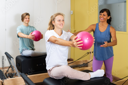 Pilates instructor shows girl how to exercise with a ball