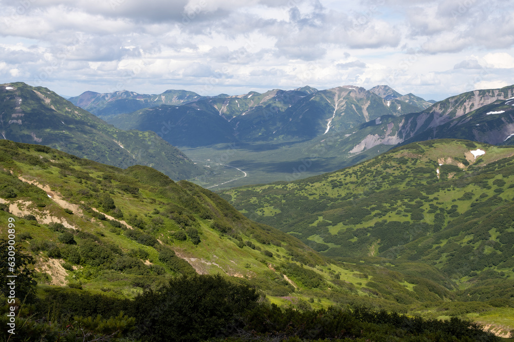 Summer mountain landscape. View from the mountains to the valley. Travel, tourism and hiking on the Kamchatka Peninsula. Beautiful nature of Siberia and the Russian Far East. Kamchatka Krai, Russia.