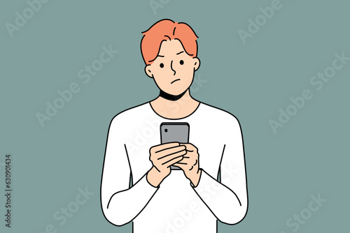 Pensive man with phone received warning text message with threat or bad news about storm warning. Confused young guy with disbelief reads spam sms in smartphone being skeptical about sender
