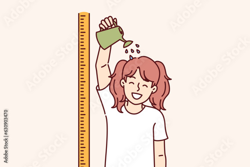 Little girl stands near ruler for measuring height and pours watering can on head, wanting to stop being child. Funny child dreams of getting taller and going to high school or college