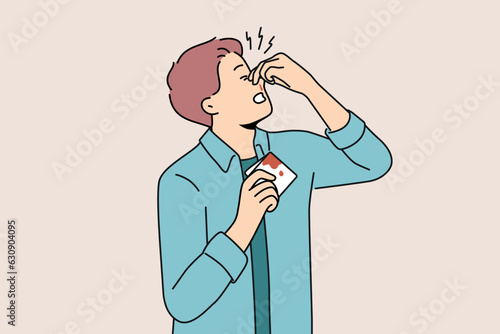 Man pinches bleeding nose and holds bloody handkerchief due to high blood pressure. Young guy with broken nose tries to stop bleeding after fighting and getting punched in face or head