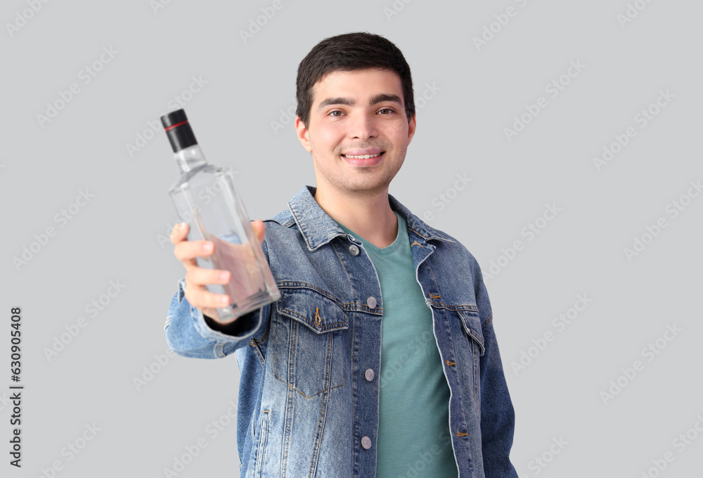 Young man with bottle of vodka on light background Young man with bottle of vodka on light background