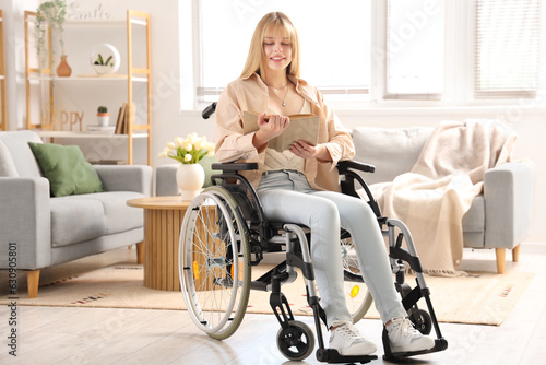 Young woman in wheelchair reading book at home