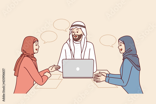 Corporate business meeting with people in arabic clothes and hijabs sitting at office table with laptop. Meeting company employees with partners for brainstorming and discussion of marketing strategy