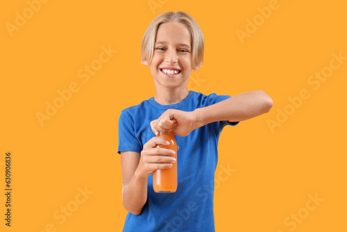 Little boy with bottle of orange juice on color background