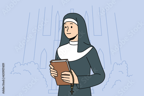 Woman nun with bible stands near church calling to visit christian shrines and study gospel or religious prayers. Catholic nun in white and black cassock holds cross for traditional orthodox rituals.