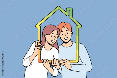 Man and woman with house outline symbolizing family property and sustainable energy efficient housing. Young couple recommends taking out mortgage or insuring house to avoid possible problems