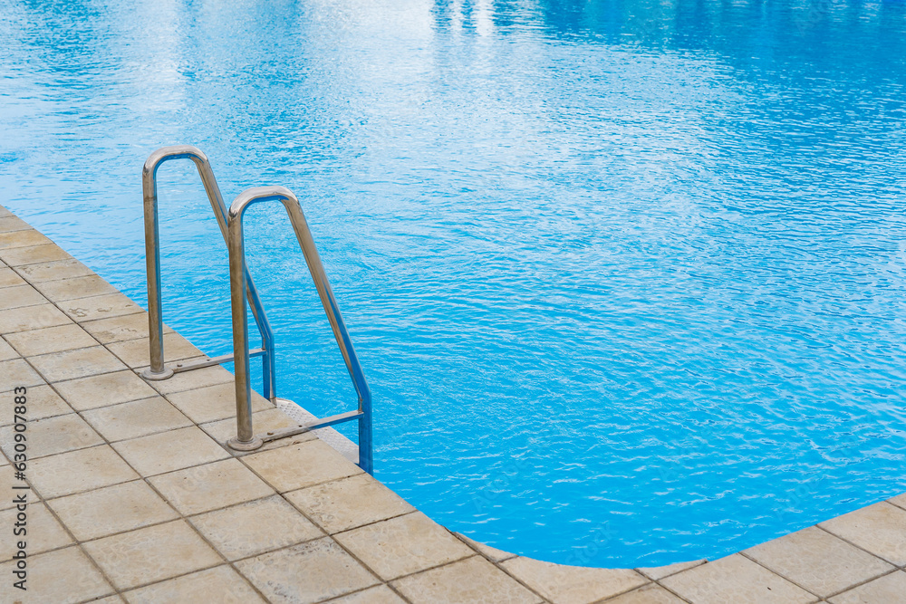 Swimming pool with selective focus on metal stairs and copy space for text.