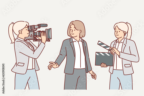 Film crew of cameraman and female assistant with clapboard near television presenter