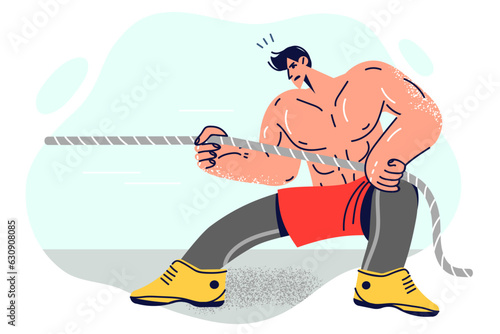 Strong muscular man pulls rope to defeat rivals in strongman sports competitions