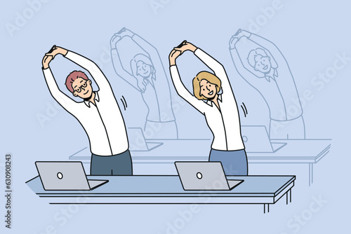 Office workers do exercises standing at workplaces and stretching arms up. Business men and women doing office fitness to increase work productivity or fight diseases associated with sedentary work