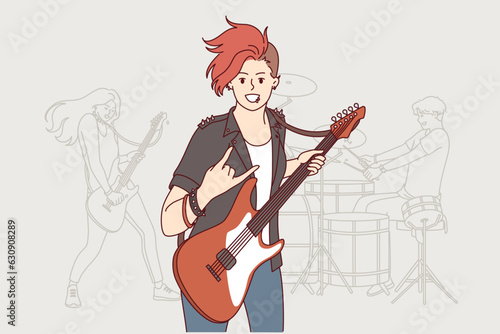 Girl rock musician plays guitar and makes gesture of goat enjoying performance at heavy music concert. Woman participating in rock band performing in nightclub with songs from new album