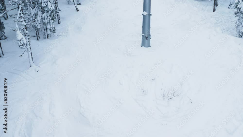 Top down camera shot of descending skiing track covered by snow on mountainside hills adorn with frosty pine trees. Extreme sport enjoyers using ski lift to reach mountain top to slide down slopes Top down camera shot of descending skiing track covered by snow on mountainside hills adorn with frosty pine trees. Extreme sport enjoyers using ski lift to reach mountain top to slide down slopes