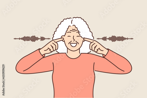 Older woman covers ears and smiles ignoring surrounding noise or refusing to listen to spoilers