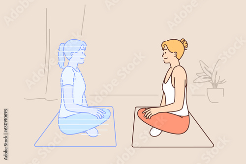 Woman doing yoga with hologram virtual trainer sitting on fitness mat in lotus position