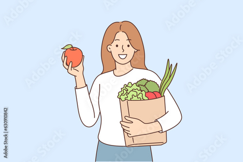 Woman buyer bought fruits and vegetables in grocery supermarket and holds paper bag