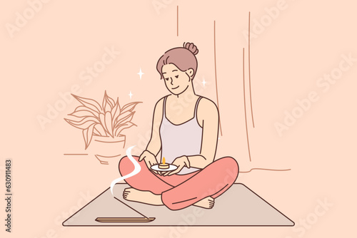 Meditating woman does yoga and uses aroma candles during spiritualistic session.