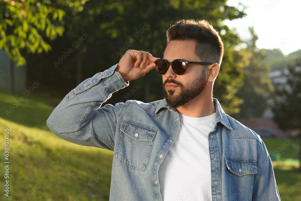 Handsome young man wearing sunglasses in park Handsome young man wearing sunglasses in park
